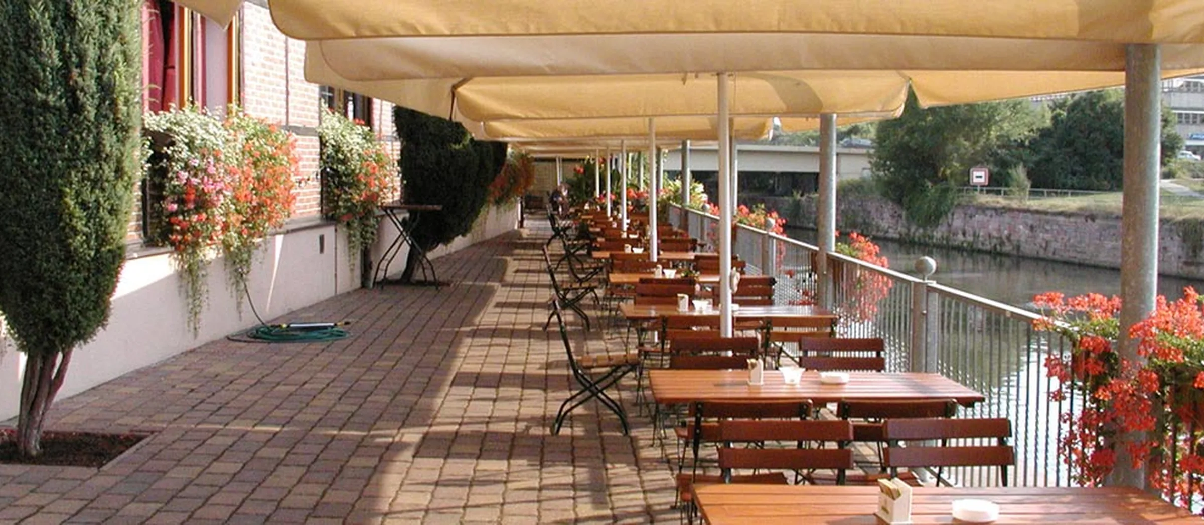 Blick auf die Außenterrasse des Saalekahns, die direkt am Wasser gelegen ist.