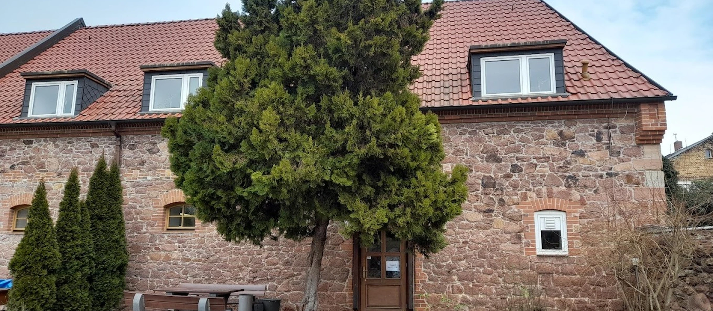 Außenansicht der Schleuse: ein alters Backsteingebäude ist zu sehen, davor steht ein Baum.