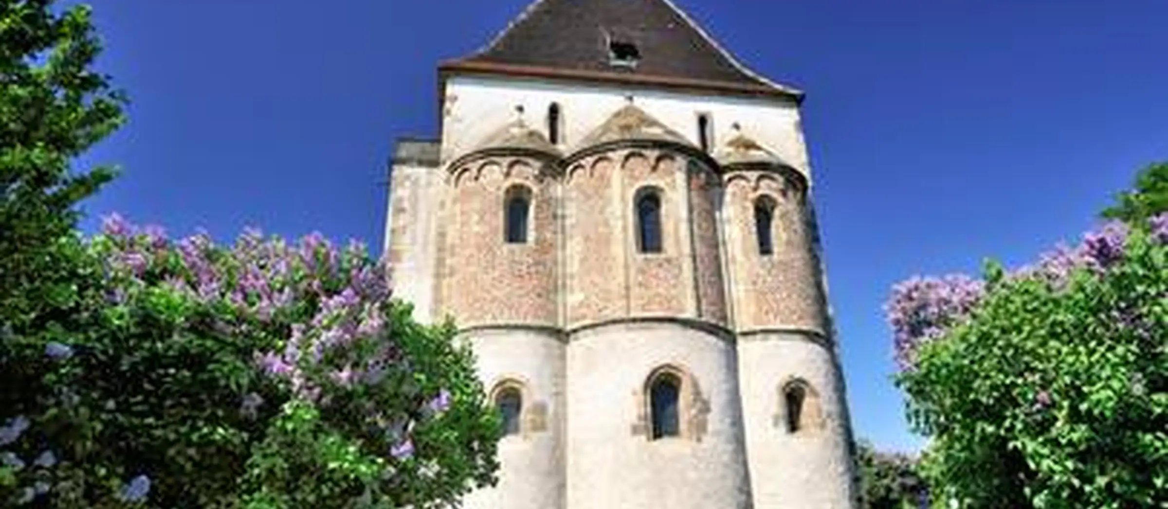 Das Bild zeigt eine kleine Kapelle inmitten einer grünen Kulisse.