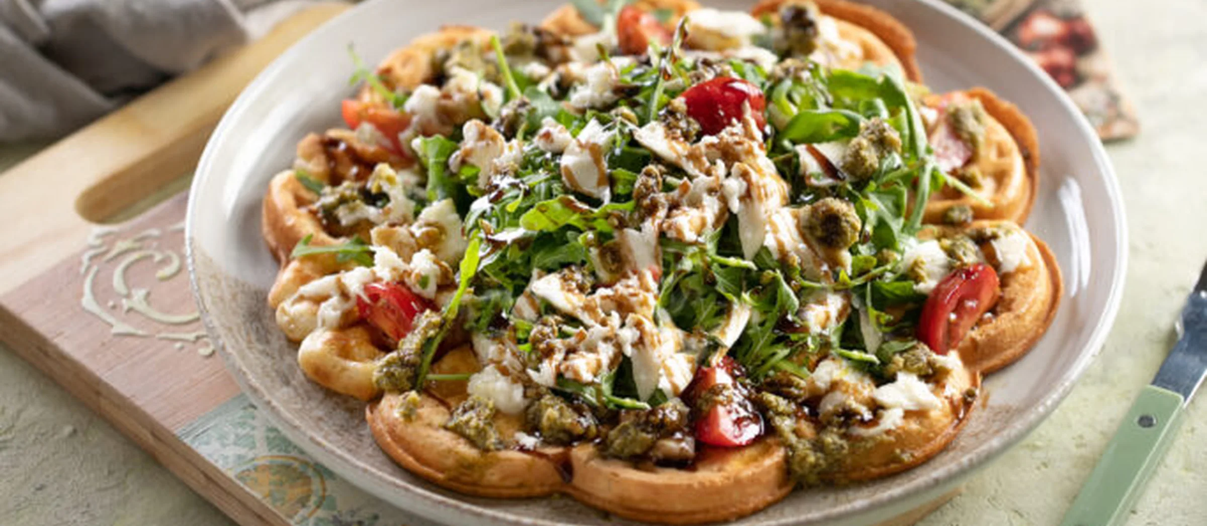 Das Bild zeigt eine herzhaft belegte Waffel mit Tomate und Mozarella