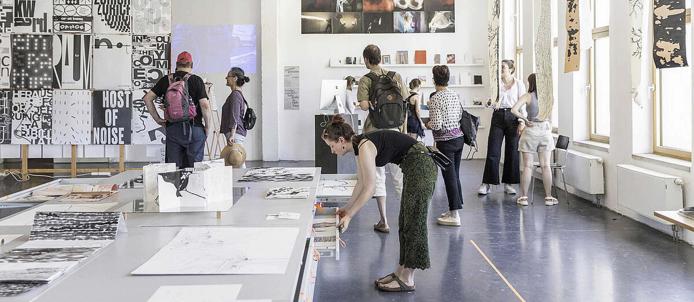 Mehrere Personen schauen sich Bilder und Objekte in der Jahresausstellung an.