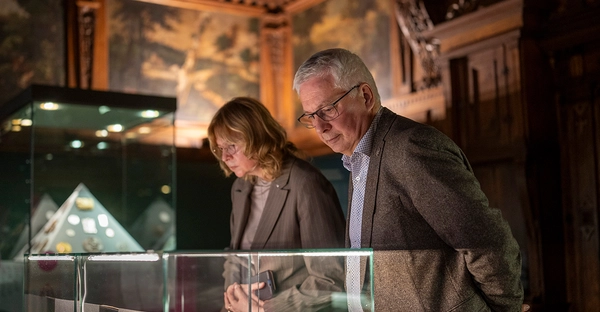 Ansicht der Ausstellung „Halle handlich. 75 Jahre Landesmünzkabinett Sachsen-Anhalt“ im Kunstmuseum Moritzburg Halle (Saale). Zwei Personen beugen sich über Museumsvitrinen. 
