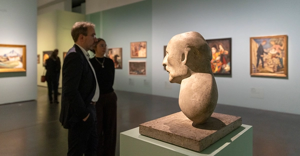 Ansicht der Ausstellung „Karl Hofer. Zwischen Schönheit und Wahrheit“ im Kunstmuseum Moritzburg Halle (Saale). Zwei Personen stehen vor Gemälden des Malers Karl Hofer. 