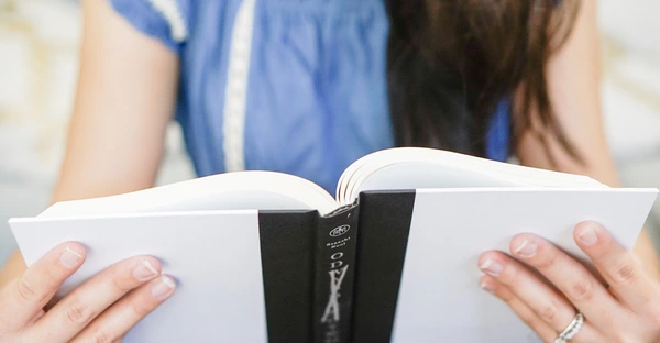 Frau hält ein aufgeschlagenes Buch in den Händen