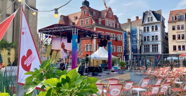 Der Marktplatz Halle ist zu sehen: Stühle stehen auf dem Boden und eine Bühne ist aufgebaut.