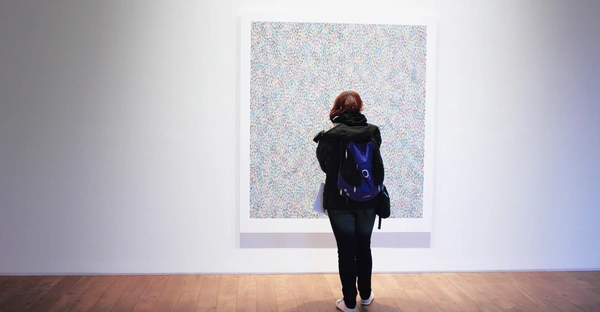 Frau schaut ein Bild in einer Ausstellung an