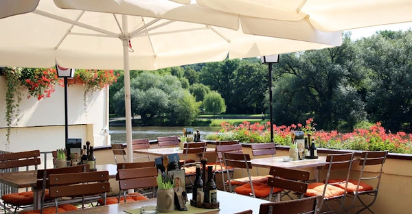 Die Terrasse des Krug zum grünen Kranze liegt direkt am Wasser und wird überdeckt von weißen Sonnenschirmen. Der Blick reicht bis zur anderen Seite des Ufers.