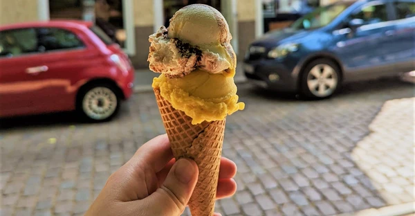 Jemand hält ein Eis mit 2 Kugeln in einer Eiswaffel in der Hand.
