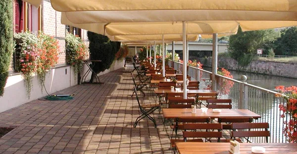 Blick auf die Außenterrasse des Saalekahns, die direkt am Wasser gelegen ist.