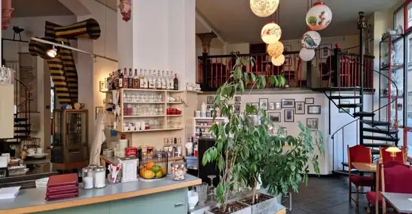 Das nt-Café ist innen geschmückt mit Pflanzen, laternenartigen Lampen und einem blau-türkisen Bartresen