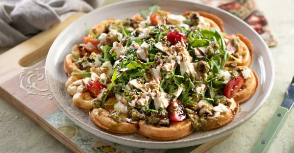 Das Bild zeigt eine herzhaft belegte Waffel mit Tomate und Mozarella