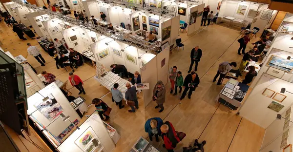 Ein Blick auf die Kunstmesse von oben. Es sind viele Stände mit Ausstellern und Künstlern zu sehen.