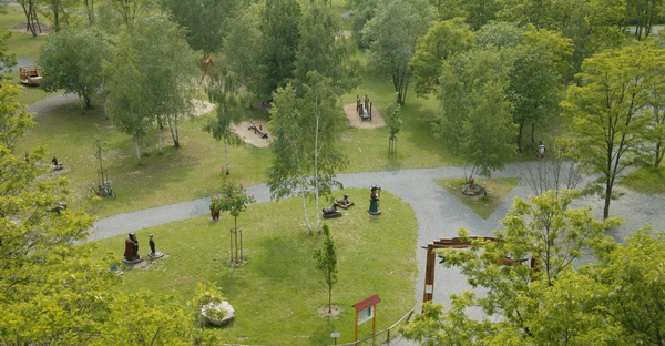 Aus der Vogelperspektive sieht man einen Park mit Wiesen und Bäumen. 